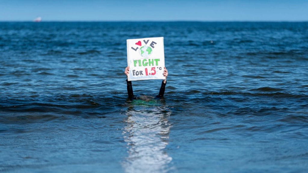 XR Forres - climate activist underwater holding up sign saying 'love earth fight for 1.5 degrees'