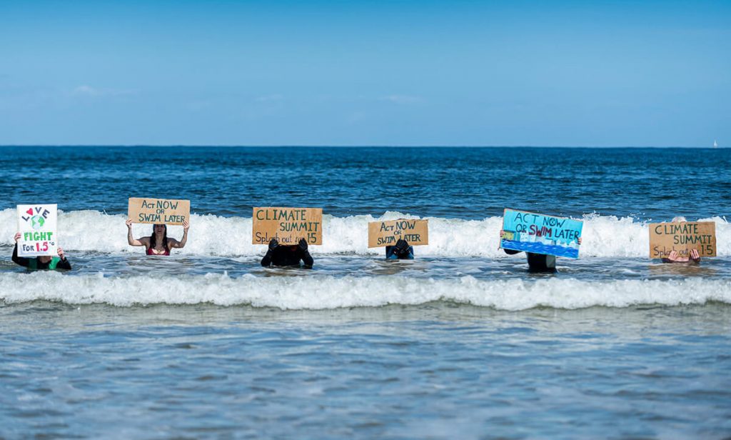 Climate activists stand in sea holidng up signs