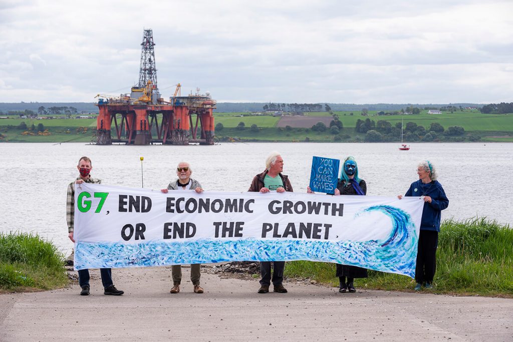 XR Inverness activists hold banner saying 'G7: End Economic Growth or End the Planet' in front of North Sea oil rig