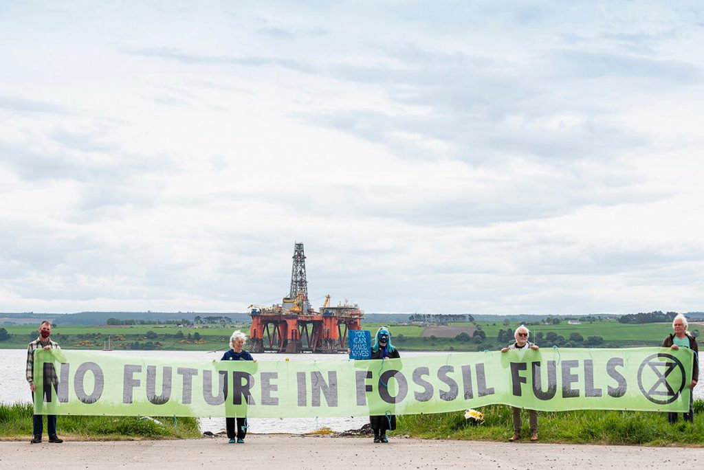 XR Inverness activists hold banner saying 'No Future in Fossil Fuels' in front of North Sea oil rig