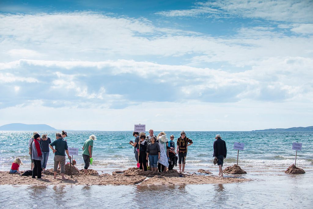 Activists stand on sand bank surrounded by sea to show affect of rising levels on small islands