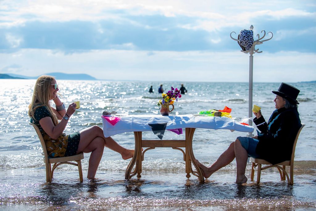 Two climate activists sit having a drink at a table in the sea