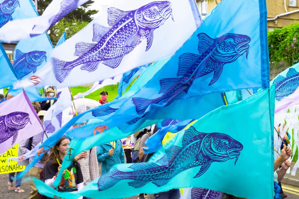 Colourful flags with fish stencilled on being carried by climate marchers