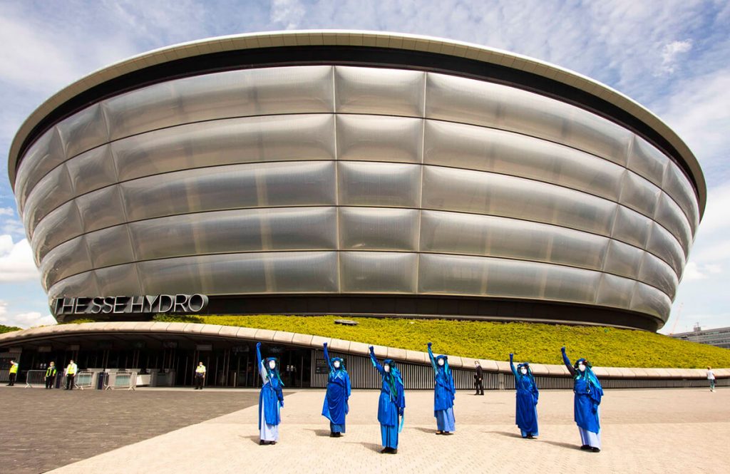 Blue Rebels each with one arm raised perform in front of Hydro