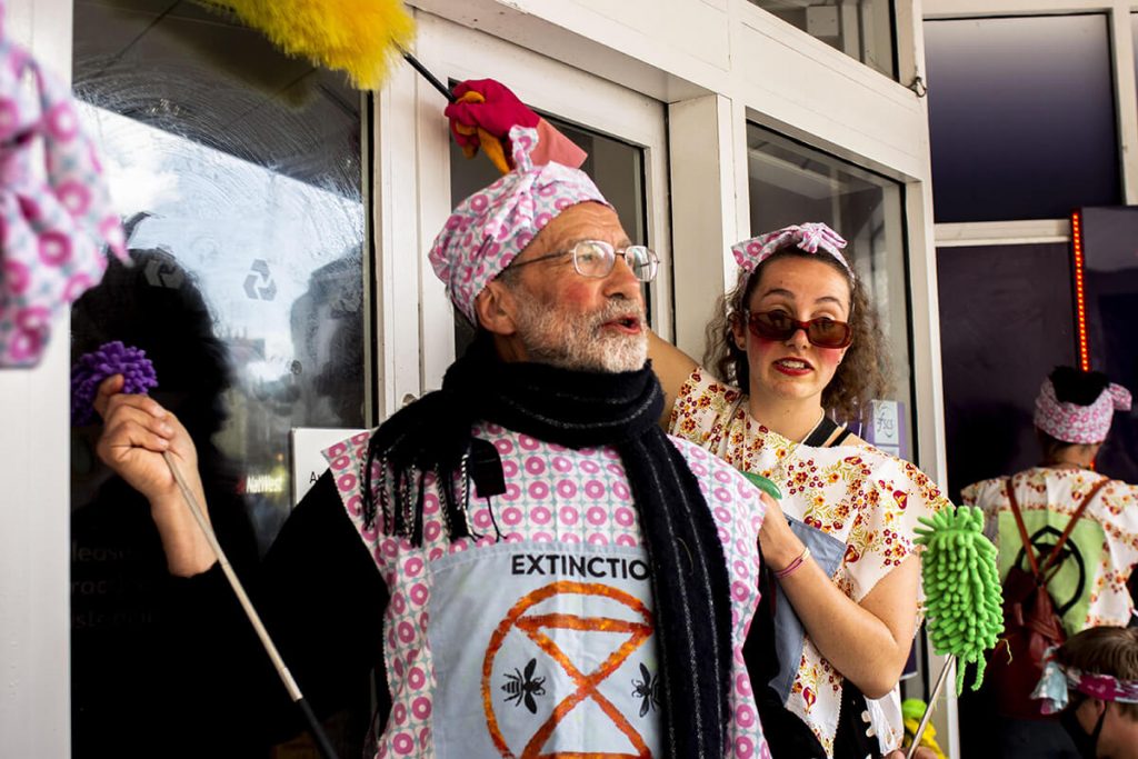 Two activists dressed as old-fashioned cleaners scrub a dirty bank (Barclays)