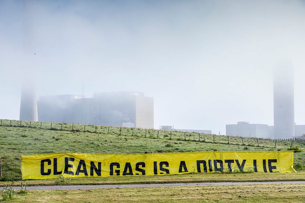 banner in foreground saying Clean Gas is a Dirty. Peterhead Power Station shrouded by fog.
