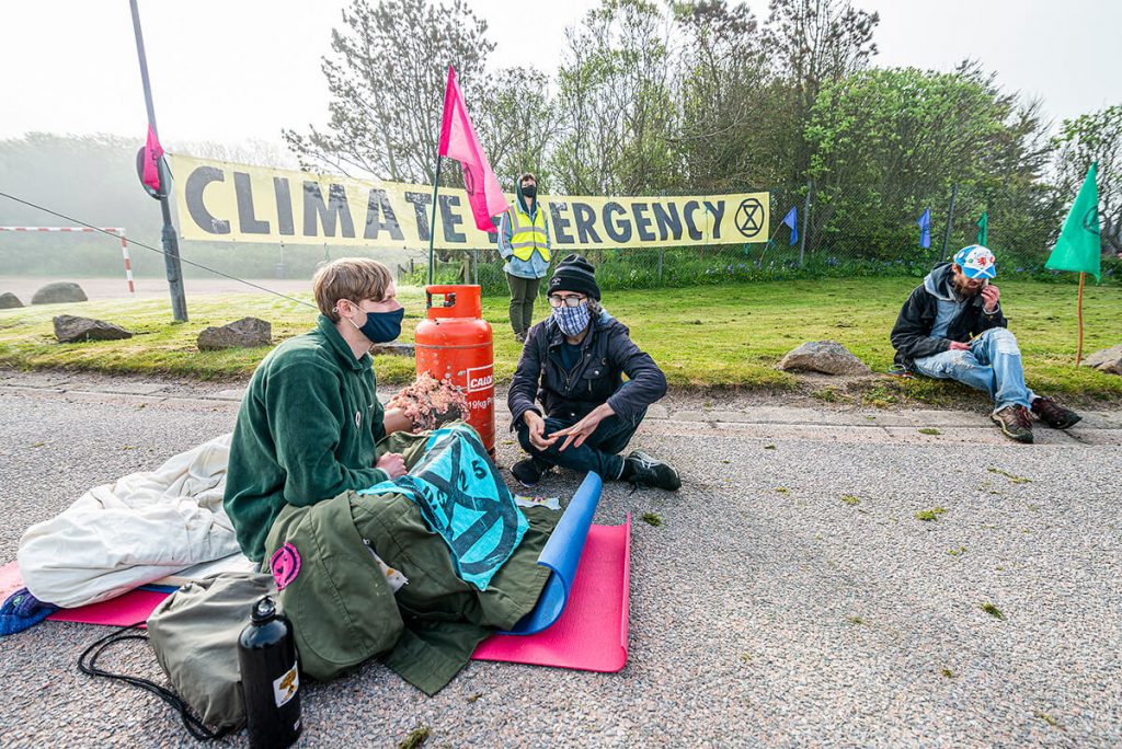 Peterhead Power Station: activist sitting on road and locked on to gas canister