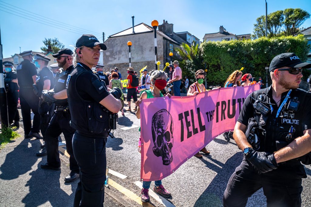 Police surround protestors holding up banner saying Tell the Truth