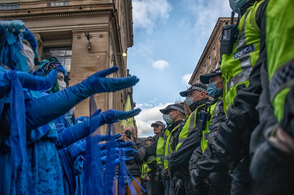 Line of Blue Rebels hold hands out to line of police at march