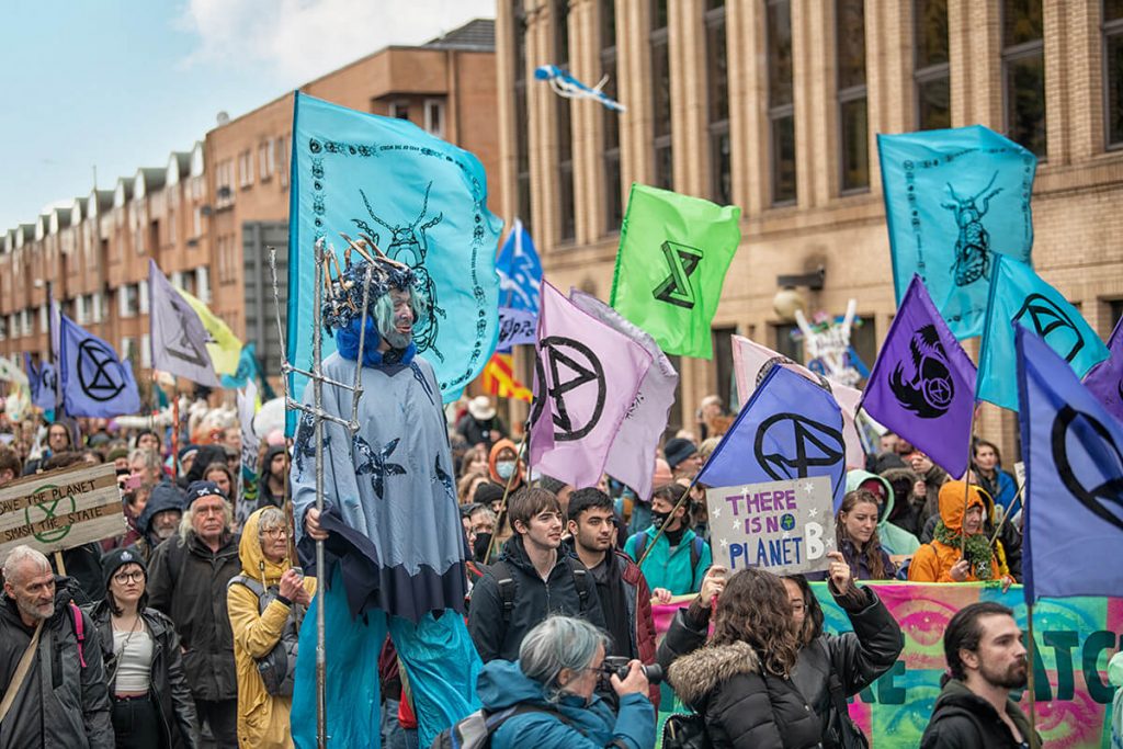 Extinction Rebellion protestors with flags and placards marching in street
