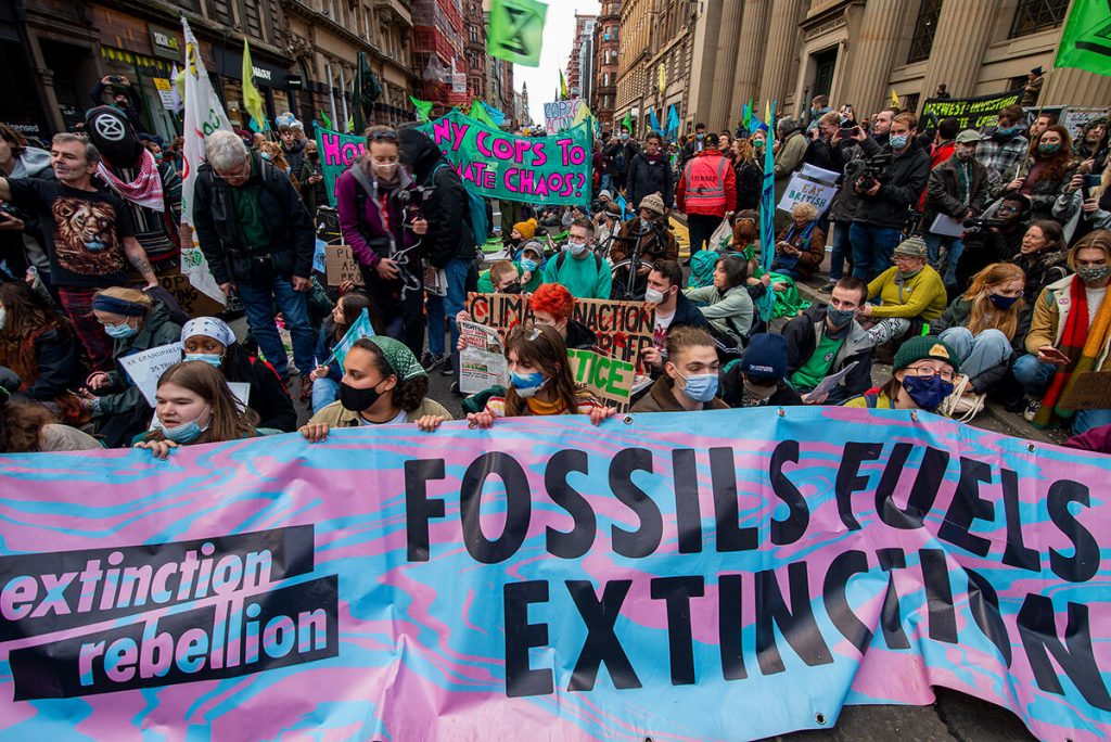 COP26: Extinction Rebellion protestors with banner that says Fossils Fuels Extinction