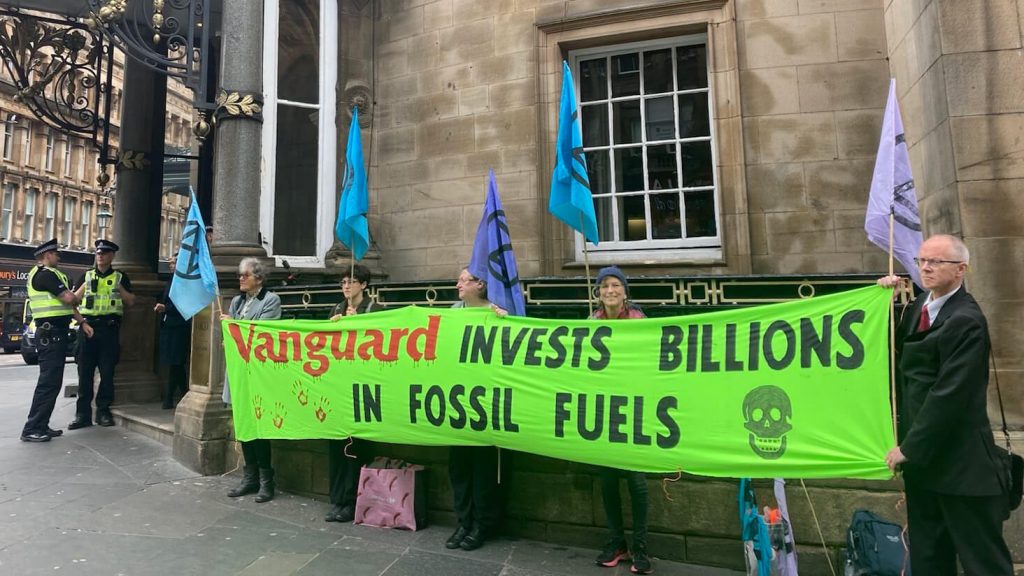 Climate activists holding up a banner saying 'Vanguard invests billions in fossil fuels'