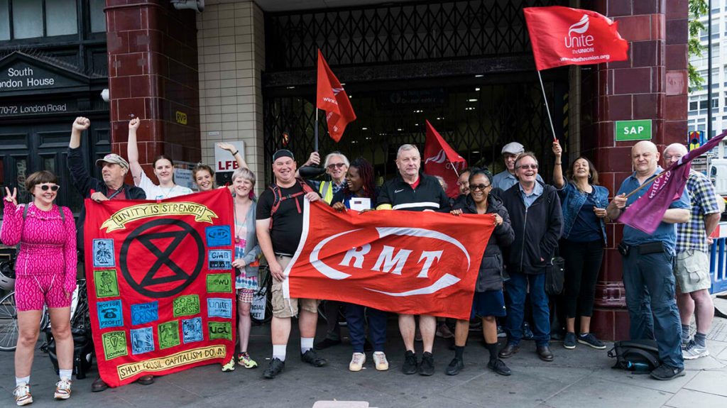 Picket line outside London underground station with RMT, XR and Unite flags